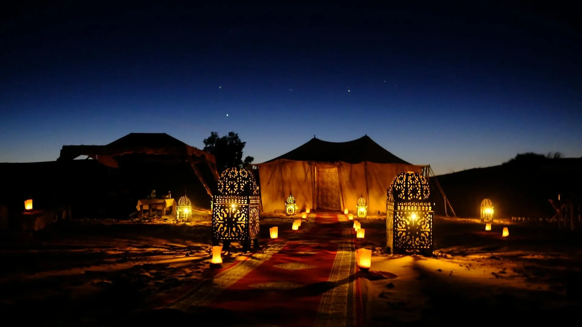 Campamento de lujo bereber iluminado de noche en las dunas del desierto del Sahara, Marruecos