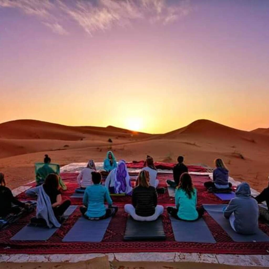 Grupo practicando yoga al amanecer entre las dunas del desierto del Sahara, Marruecos